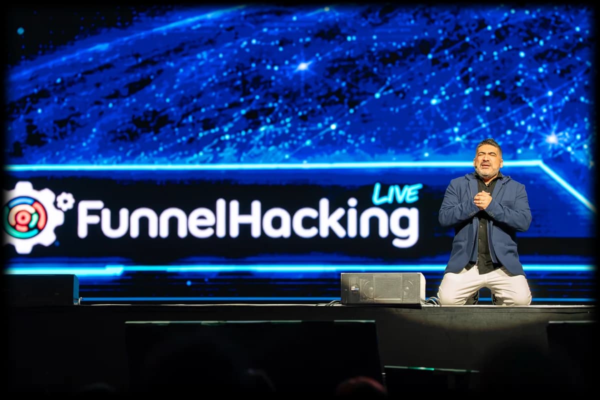 Miguel Carrasco kneeling on stage beneath the Funnel Hacking Live wordmark